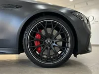 The dark metallic grey Mercedes-Benz C63 AMG showcases its front wheel with black multi-spoke rim and red brake caliper in Alicante.