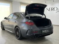 The dark metallic grey Mercedes-Benz C63 AMG is shown from the rear three-quarter angle with its trunk open in Alicante.