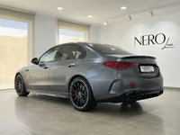 The dark grey matte Mercedes-Benz C63 AMG is showcased from a rear three-quarter angle in a bright Alicante showroom.