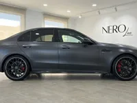 The dark metallic grey 2024 Mercedes-Benz C63 AMG is showcased in a full side profile view inside a showroom in Alicante.