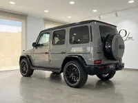 The gloss Arabian Grey Mercedes-Benz G63 AMG is displayed from its rear three-quarter angle inside a modern showroom in Ibiza.
