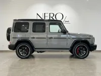 The gloss Arabian Grey Mercedes-Benz G63 AMG is shown from a side profile in a bright showroom in Ibiza.