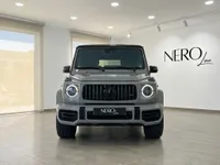 The front view of a gloss Arabian Grey Mercedes-Benz G63 AMG, parked in a showroom with the Nero Line logo on the wall in Ibiza.