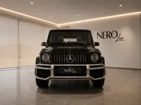 The front view of a gloss Obsidian Black Mercedes-Benz G63 AMG luxury SUV parked indoors in Lausanne.