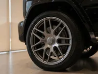 Close-up of the Mercedes-Benz G63 AMG's multi-spoke alloy wheel and tire in gloss Obsidian Black, available in Lausanne.
