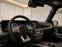 View of the Mercedes-Benz G63 AMG's luxurious interior in Lausanne, highlighting the steering wheel, digital dashboard, and infotainment system.