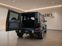 The rear view of a black Mercedes-Benz G63 AMG with its trunk open, showcasing its spacious cargo area in Lausanne.