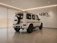 The white Mercedes-Benz G63 AMG is showcased from a rear three-quarter view in a modern showroom in Lausanne.