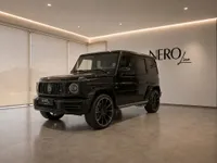 A gloss black Mercedes-Benz G63 Brabus is showcased in a modern showroom with the NEROline logo in Lausanne.