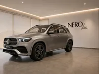 A metallic silver Mercedes-Benz GLE 350d SUV is parked in a modern showroom with the NEROline logo, Lausanne.