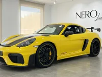 تُعرض سيارة بورش 718 كايمان GT4 RS الصفراء الزاهية من زاوية أمامية ثلاثية الأرباع في صالة عرض حديثة في أليكانتي.