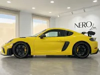 تُعرض سيارة بورش 718 كايمان GT4 RS الصفراء اللامعة من الجانب داخل صالة عرض حديثة في أليكانتي بإسبانيا.