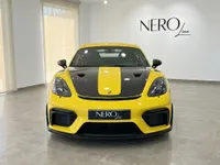 بورشه 718 كايمان GT4 RS باللون الأصفر اللامع مع شريط أسود، منظر أمامي، في صالة عرض بأليكانتي، إسبانيا.