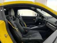 التصميم الداخلي لسيارة بورش 718 كايمان GT4 RS في أليكانتي، يتميز بمقاعد رياضية سوداء وأحزمة أمان صفراء ولوحة قيادة مفصلة.