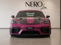 The striking gloss Ruby Star Neo Porsche 718 Cayman GT4 RS is showcased from the front view inside the Nero Line showroom in Zurich.