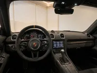 The interior cockpit of the Porsche 718 Cayman GT4 RS in Zurich, showcasing the steering wheel, dashboard, and infotainment system.