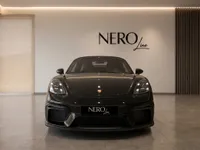 The gloss black 2021 Porsche 718 Spyder is showcased from a front view in a modern Zurich showroom.