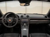 The luxurious black interior of the Porsche 718 Spyder, featuring the steering wheel, dashboard, and center console, available for rent in Zurich.