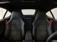 The Porsche 718 Spyder interior in Zurich features black leather and Alcantara seats with red stitching, 'Spyder' logos, and red seatbelts.