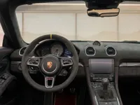 The image shows the luxurious cockpit of the 2024 Porsche 718 Spyder RS in Zurich, featuring a suede steering wheel and dashboard.
