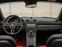 The luxurious cockpit of the Porsche 718 Spyder RS, featuring a sporty steering wheel, manual transmission, and carbon fiber seats in Zurich.