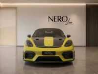 The yellow 2024 Porsche 718 Spyder RS with a carbon fiber hood stripe is presented in a showroom in Zurich.