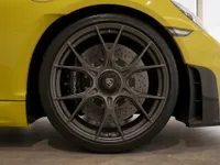 Close-up of the front wheel and carbon fiber aerodynamic elements on the yellow Porsche 718 Spyder RS in Zurich.