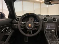 The luxurious interior of the Porsche 718 Spyder RS in Zurich, featuring its steering wheel, dashboard, and infotainment system.