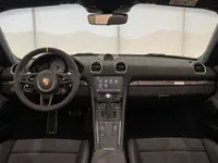 The luxurious black interior of the Porsche 718 Spyder RS in Zurich, featuring its steering wheel, dashboard, and infotainment system.