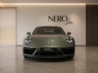 Front view of the gloss Aventurine Green Metallic Porsche 911 Carrera 4 GTS parked in a modern studio in Zurich.