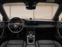 The luxurious black leather cockpit and dashboard of the Porsche 911 Carrera 4 GTS Aerokit in Zurich, featuring red stitching and modern displays.