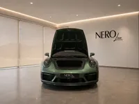 The front view of a gloss Aventurine Green Metallic Porsche 911 Carrera 4 GTS Aerokit with its hood open in a Zurich showroom.