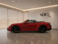 A glossy red Porsche 911 Carrera 4 GTS Cabriolet is parked in a showroom with the NeroLine logo in Zurich.