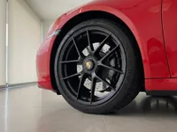 Close-up of the front wheel and red bodywork of the Porsche 911 Carrera 4 GTS Cabriolet in Zurich.