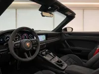 The luxurious cockpit of the Porsche 911 Carrera 4 GTS Cabriolet in Zurich, featuring a black interior with red accents and a prominent steering wheel.