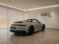 The grey Porsche 911 Carrera 4 GTS Cabriolet is parked indoors, showcasing its rear three-quarter view with the NEROline logo in Zurich.