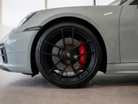 Close-up view of the front wheel and red brake caliper on the gloss light grey Porsche 911 in Zurich.