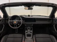 The luxurious interior of the Porsche 911 Carrera 4 GTS Cabriolet in Zurich, showcasing its modern dashboard, steering wheel, and open-top design.
