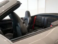 The interior of the Porsche 911 Carrera 4 GTS Cabriolet in Zurich, showing the black leather seats with red stitching and seatbelts.