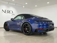 سيارة بورش 911 كاريرا 4S كابريو الزرقاء موديل 2022 معروضة من زاوية خلفية ثلاثية الأرباع في صالة عرض بإيبيزا.