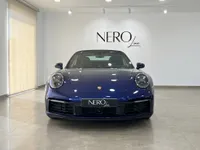 المنظر الأمامي لسيارة بورش 911 كاريرا 4S كابريو 2022 بلون أزرق جنطيانا لامع معدني، مركونة بالداخل في إيبيزا.