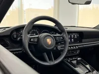 المقصورة الداخلية لسيارة بورش 911 كاريرا 4S كابريو في إيبيزا، تعرض عجلة القيادة الجلدية السوداء ولوحة القيادة الرقمية.