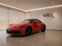 A red Porsche 911 Carrera 4S Cabriolet is showcased in a modern showroom with the NeroLine logo, in Lausanne.