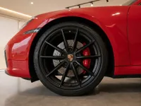 The front wheel and fender of a red Porsche 911 Carrera 4S Cabriolet with black multi-spoke wheels and red brake calipers, in Lausanne.
