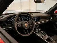 The luxurious black leather interior of the Porsche 911 Carrera 4S Cabriolet, featuring its dashboard, steering wheel, and center console in Lausanne.