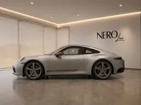 The gloss GT Silver Metallic Porsche 911 Carrera T is showcased in a modern showroom in Zurich, viewed from its elegant side profile.