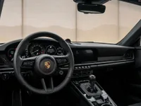The luxurious black interior of the Porsche 911 Carrera T, featuring the steering wheel, dashboard, and gear shifter, in Zurich.