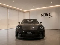 Porsche 911 GT3 in gloss black, shown from the front in a showroom with the NEROline logo in Lausanne.