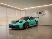 A Gloss Mint Green Porsche 911 GT3 RS is showcased in a modern showroom, viewed from the front-three-quarter angle in Zurich.