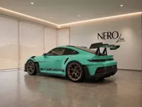The Gloss Mint Green Porsche 911 GT3 RS is showcased from a rear three-quarter angle in a modern Zurich showroom.